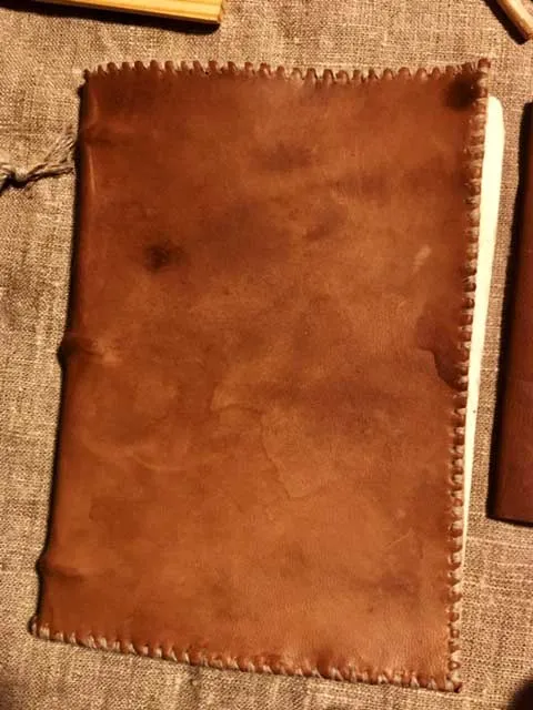A small hand-bound notebook in tan leather, on linen