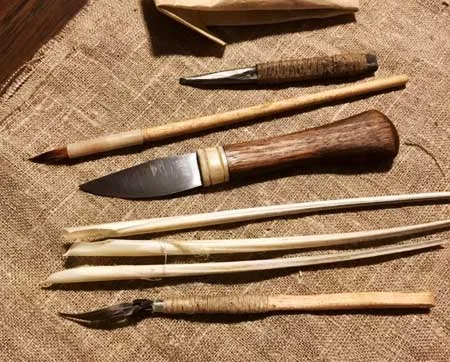 A knife, pens and styluses laid out on linen